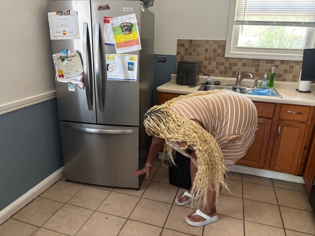 Cassandra Montgomery indicates how high the floodwater reached in the kitchen of her daughter, Aleiya Jennings' home on Minocqua Street, Park Forest on July 6, 2026. (Evy Lewis/Daily Southtown)