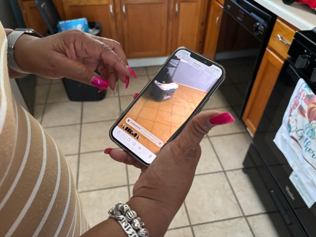 Cassandra Montgomery shows videos of floodwater washing through Aleiya Jennings' home on Minocqua Street, Park Forest on July 6, 2026. (Evy Lewis/Daily Southtown)