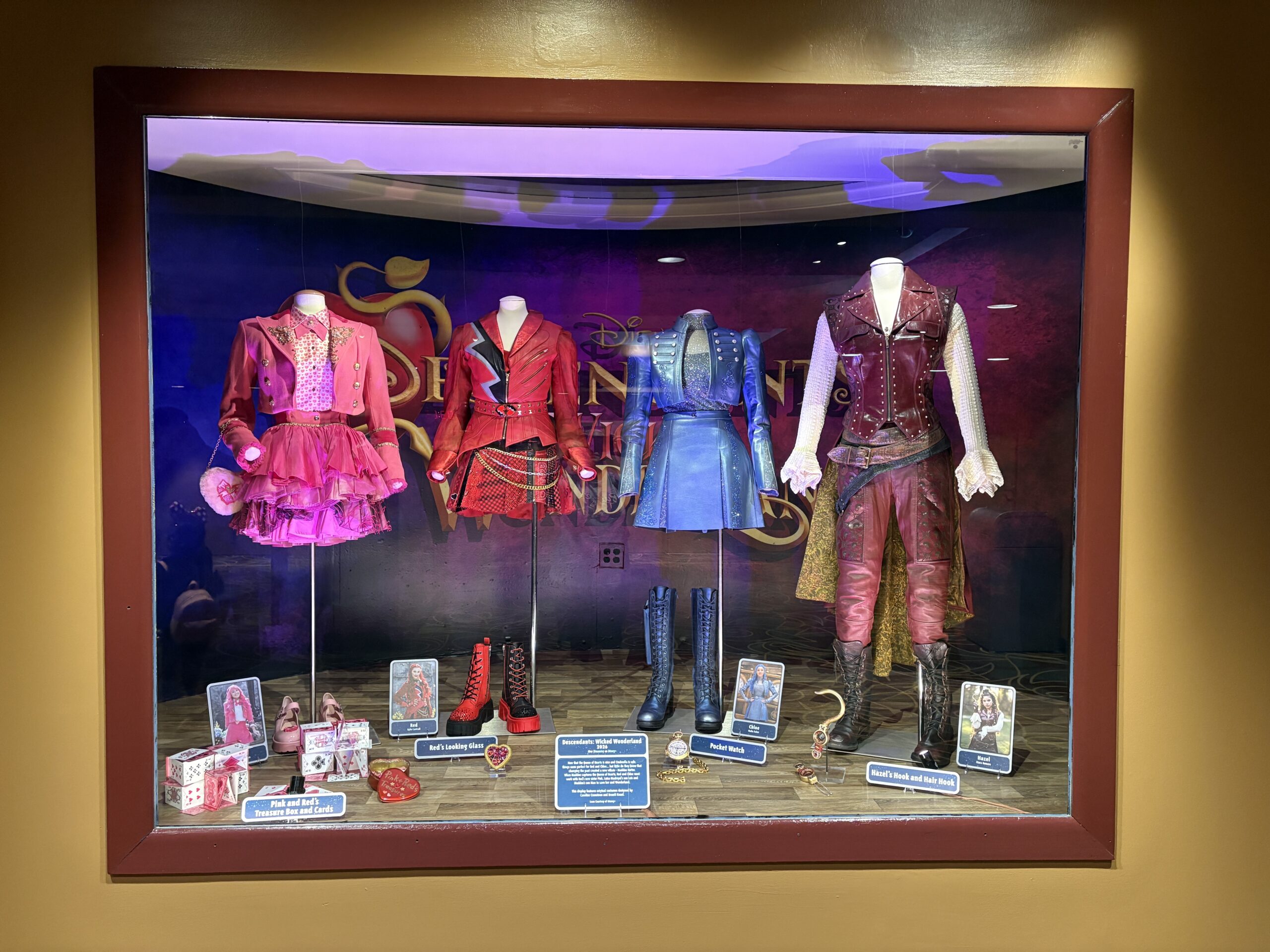 Moving on to the descendants themselves, four costumes are together in a single display. There are costumes and props for Pink (Liamani Segura), Red (Kylie Cantrall), Chloe (Malia Baker), and Hazel (Kiara Romero).