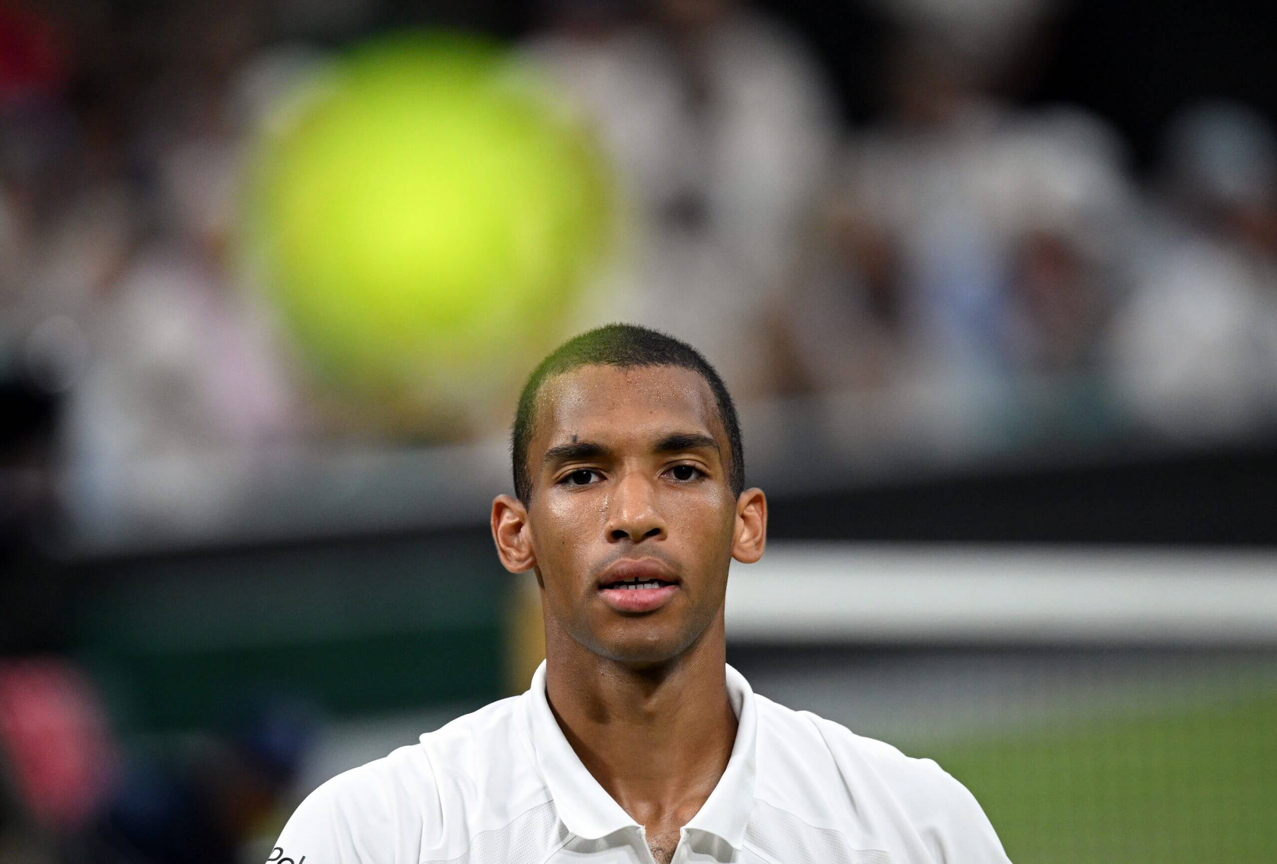 Félix Auger-Aliassime looks on as a tennis ball floats past him.