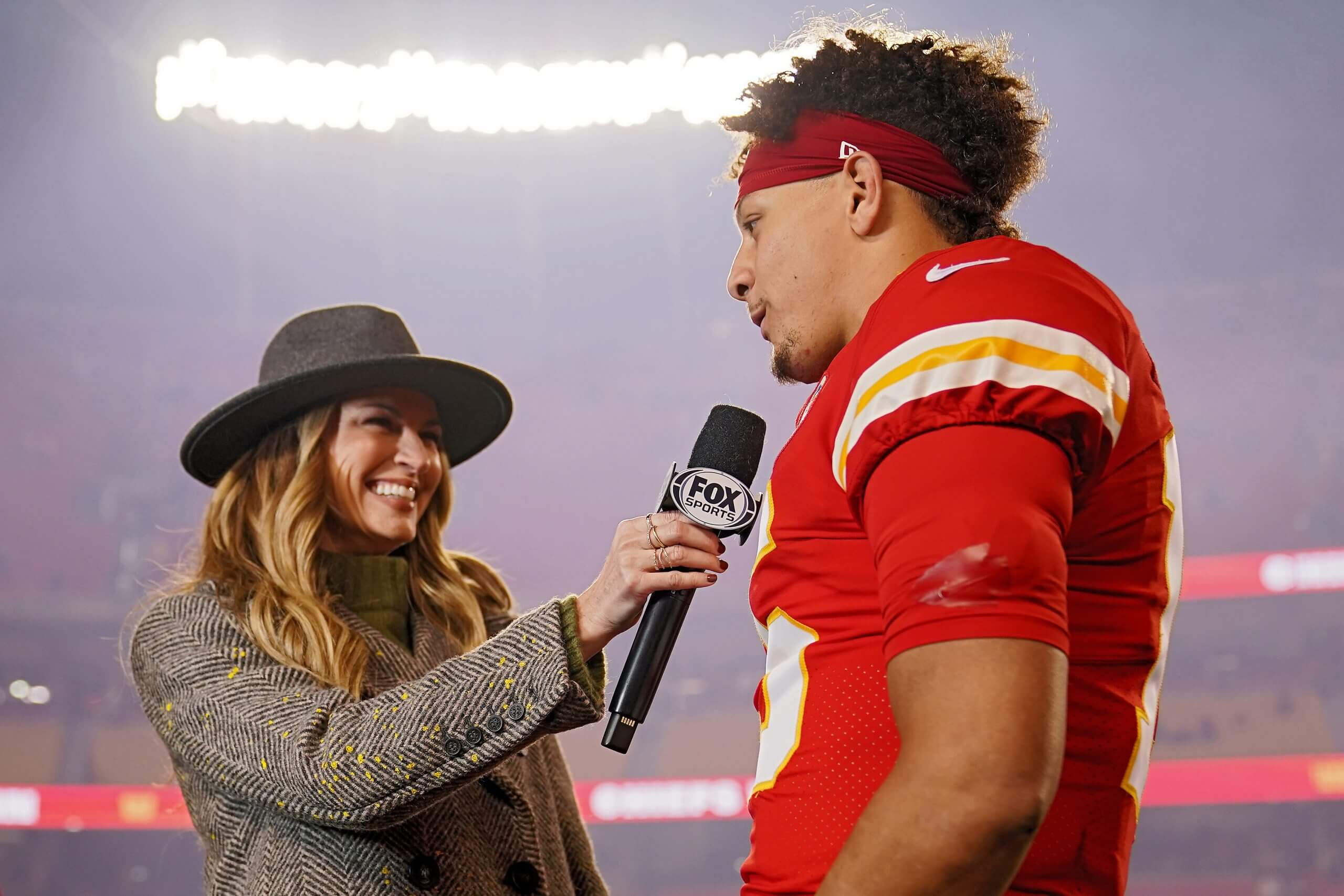 Kansas City Chiefs quarterback Patrick Mahomes, wearing a red #15 jersey, is interviewed by Fox's Erin Andrews, wearing a coat and wide-brim hat, after a game against the Los Angeles Rams.