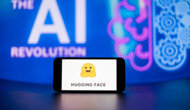 In this photo illustration, the Hugging Face logo seen displayed on a mobile phone screen with the AI (artificial intelligence) revolution symbol in the background.