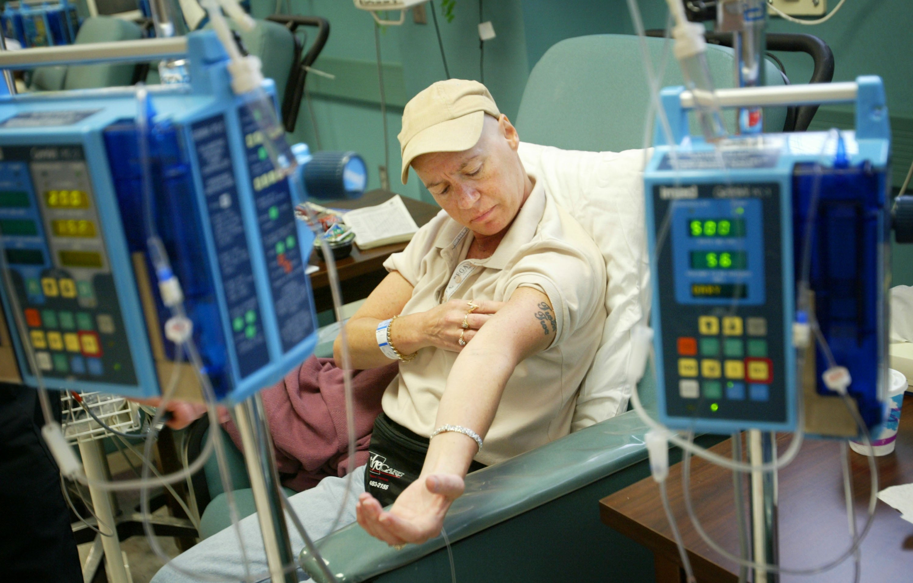 Cancer patient Ellen Walsh checks her arm during chemotherapy treatment in Fayetteville, North Carolina, in June 2003. The high costs of cancer care can prevent Americans from seeking treatment they need