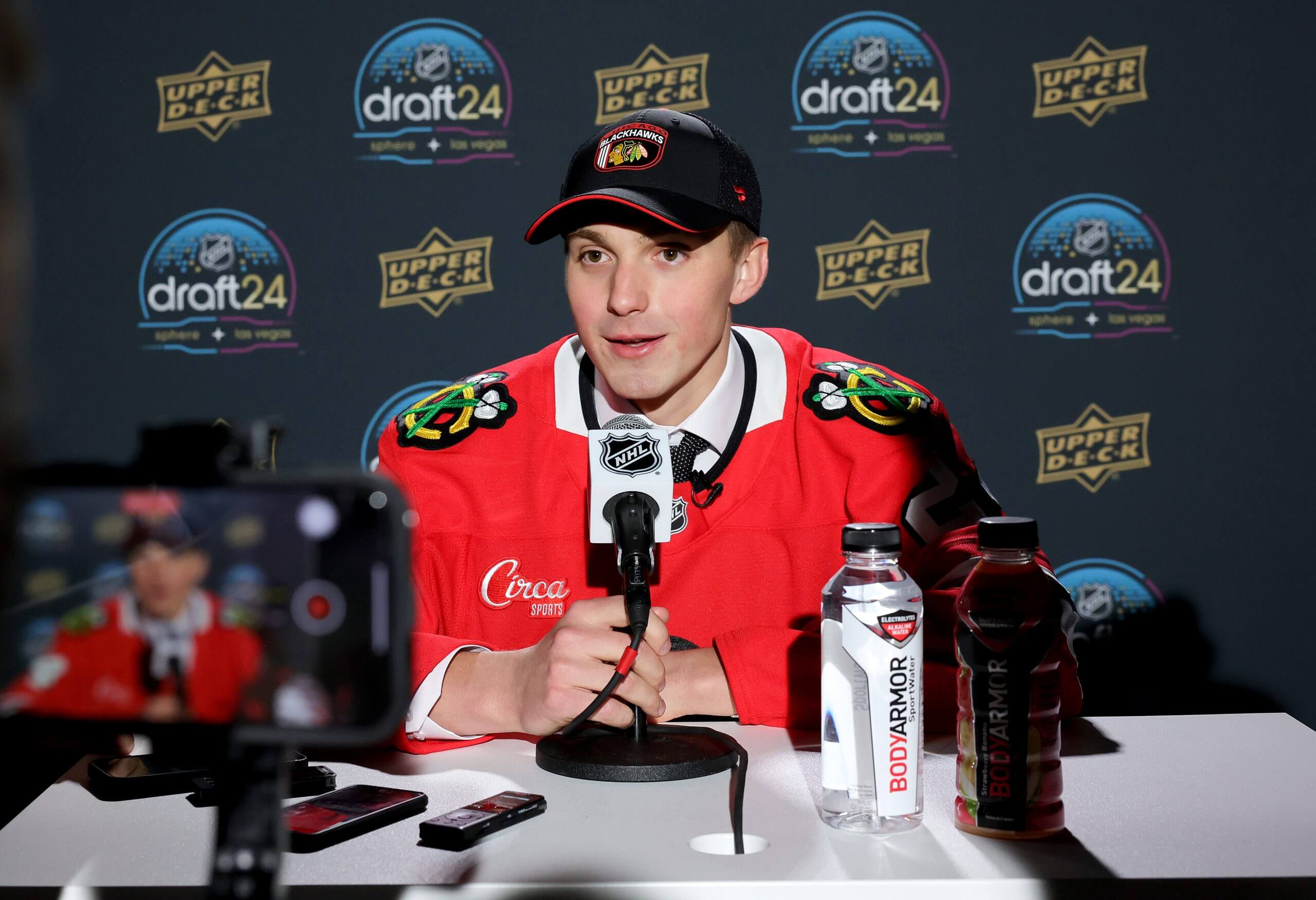 Artyom Levshunov answers questions in a Blackhawks jersey at the 2024 draft.