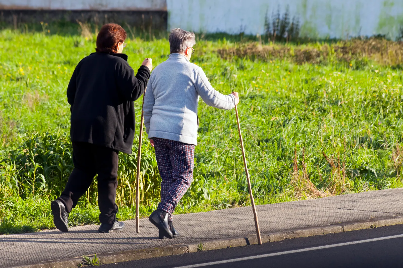 Rear view of two senior women walking together along country road a sunny afternoon. A Coruña province, Galicia, Spain.