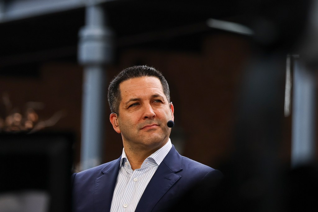 A man in a suit with a microphone by his mouth.