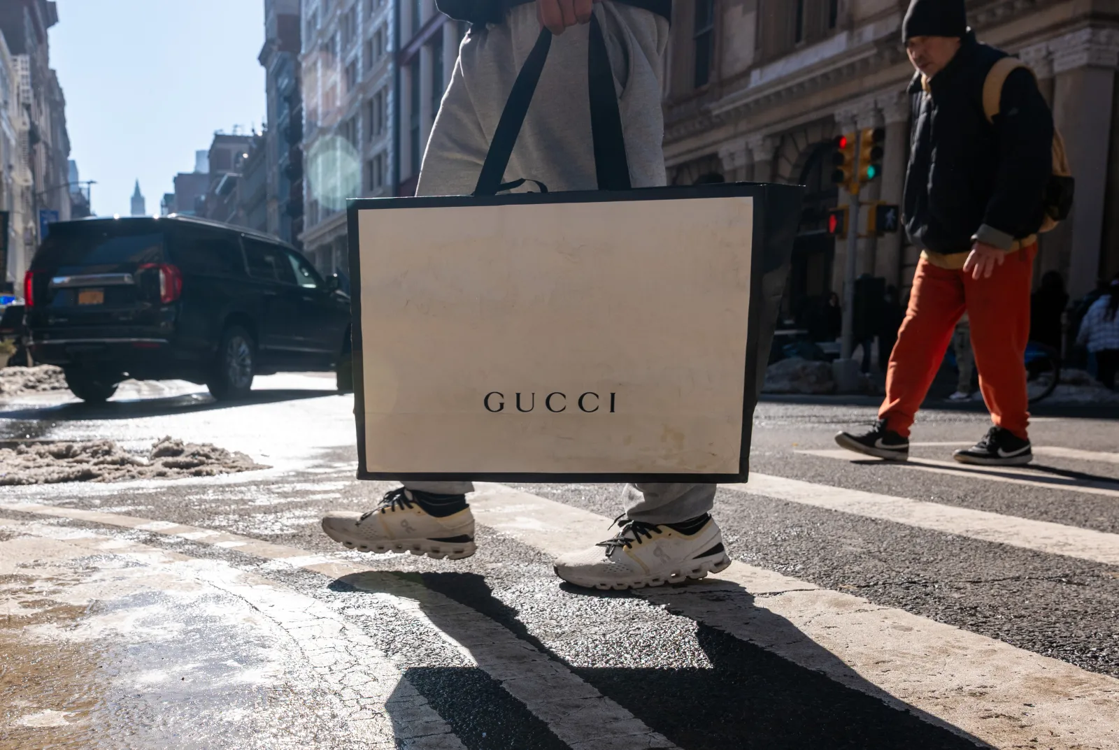 A pedestrian crosses the street with a Gucci shopping bag on February 27, 2026, in New York City.