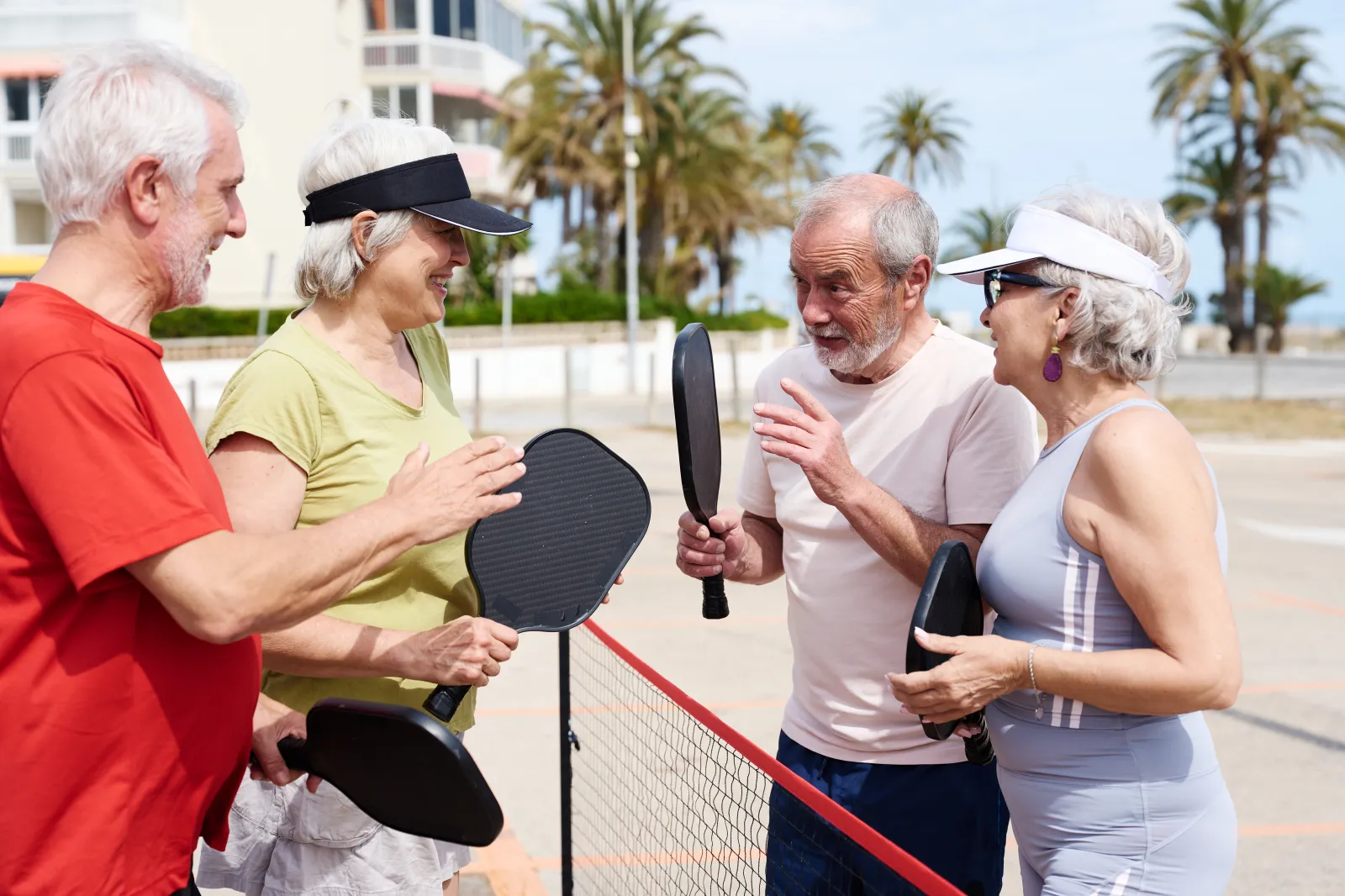 Group of senior friends engaging in a lively pickleball game outdoors, staying active and social during retirement