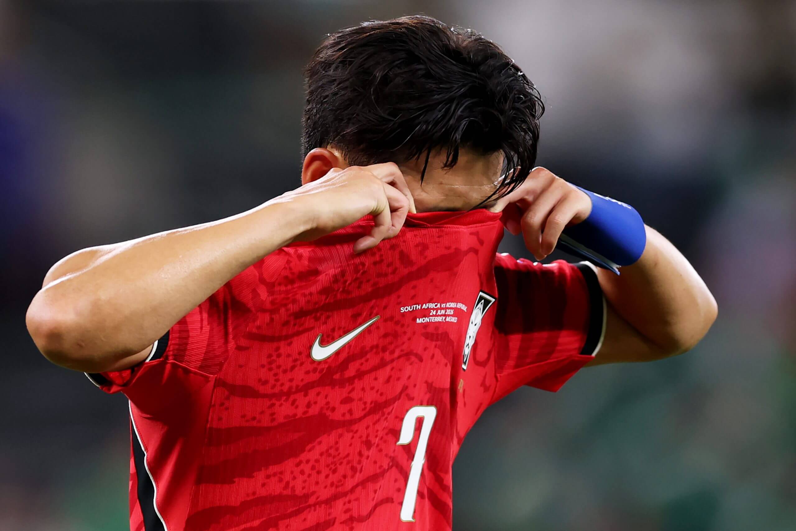 Son Heung-Min buries his face in his shirt after South Korea's exit