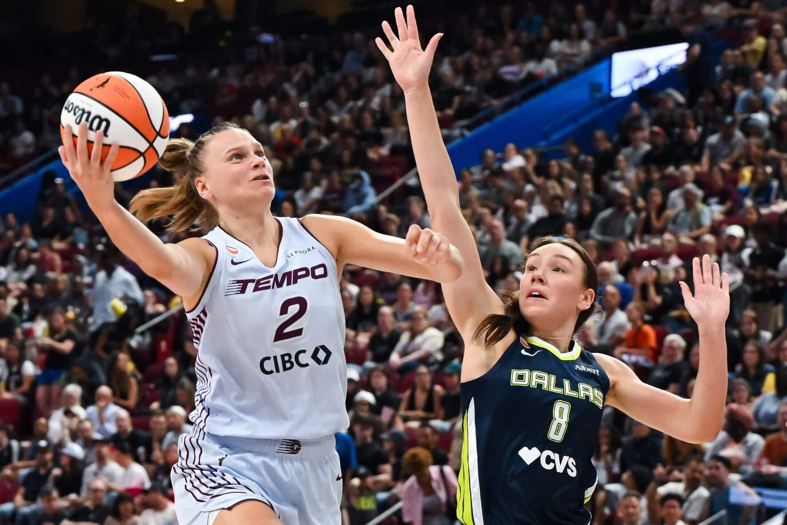 Alanna Smith (right) raises her right hand to challenge a Toronto Tempo player's shot during a WNBA game.