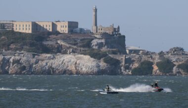 A jet ski and a boat off the coast of an island.