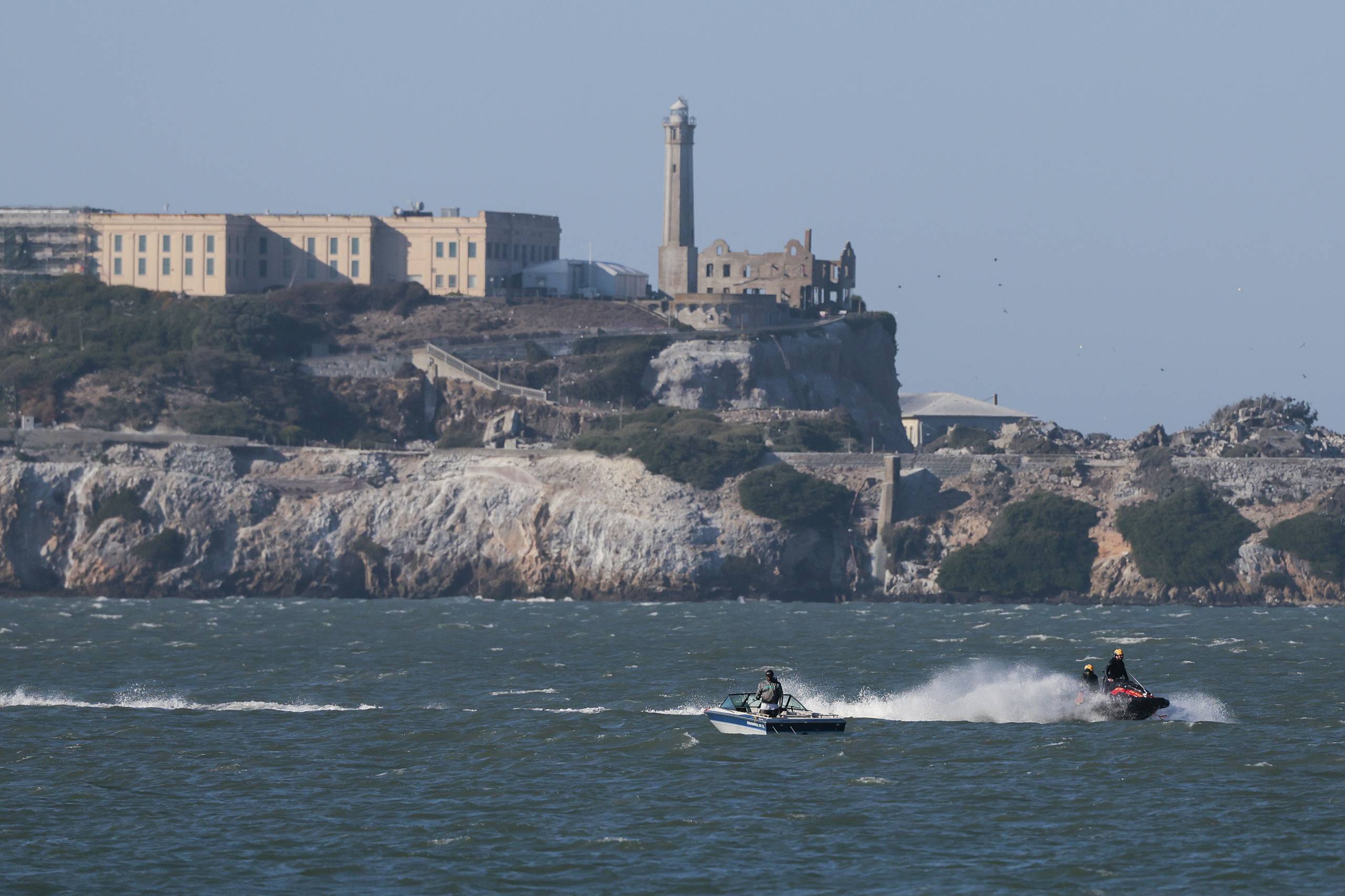 A jet ski and a boat off the coast of an island.