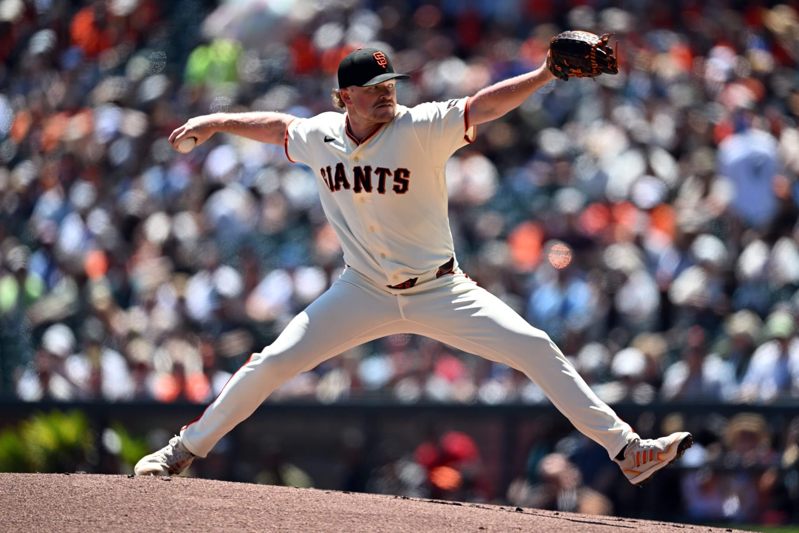 Logan Webb prepares to deliver a pitch, holding his glove at the level of his head.