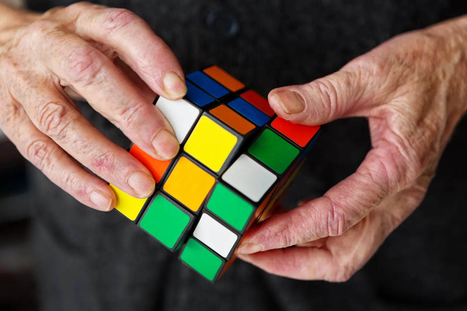 Cape Town, South Africa - June 9, 2016:  An elderly person's hands manipulate a Rubik's Cube, hopefully keeping his or her mind active.