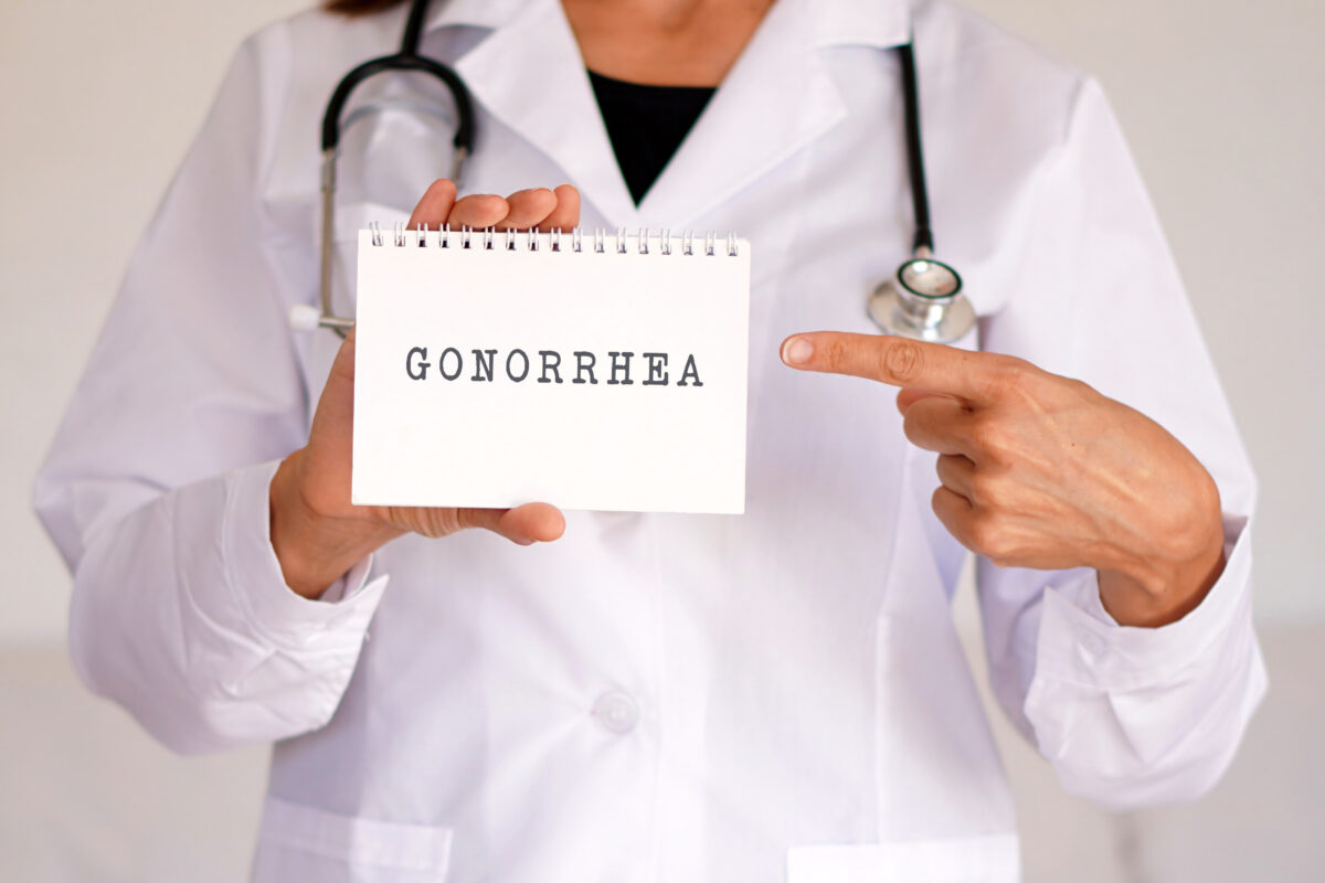 Doctor holding a card that says "Gonorrhea" on it