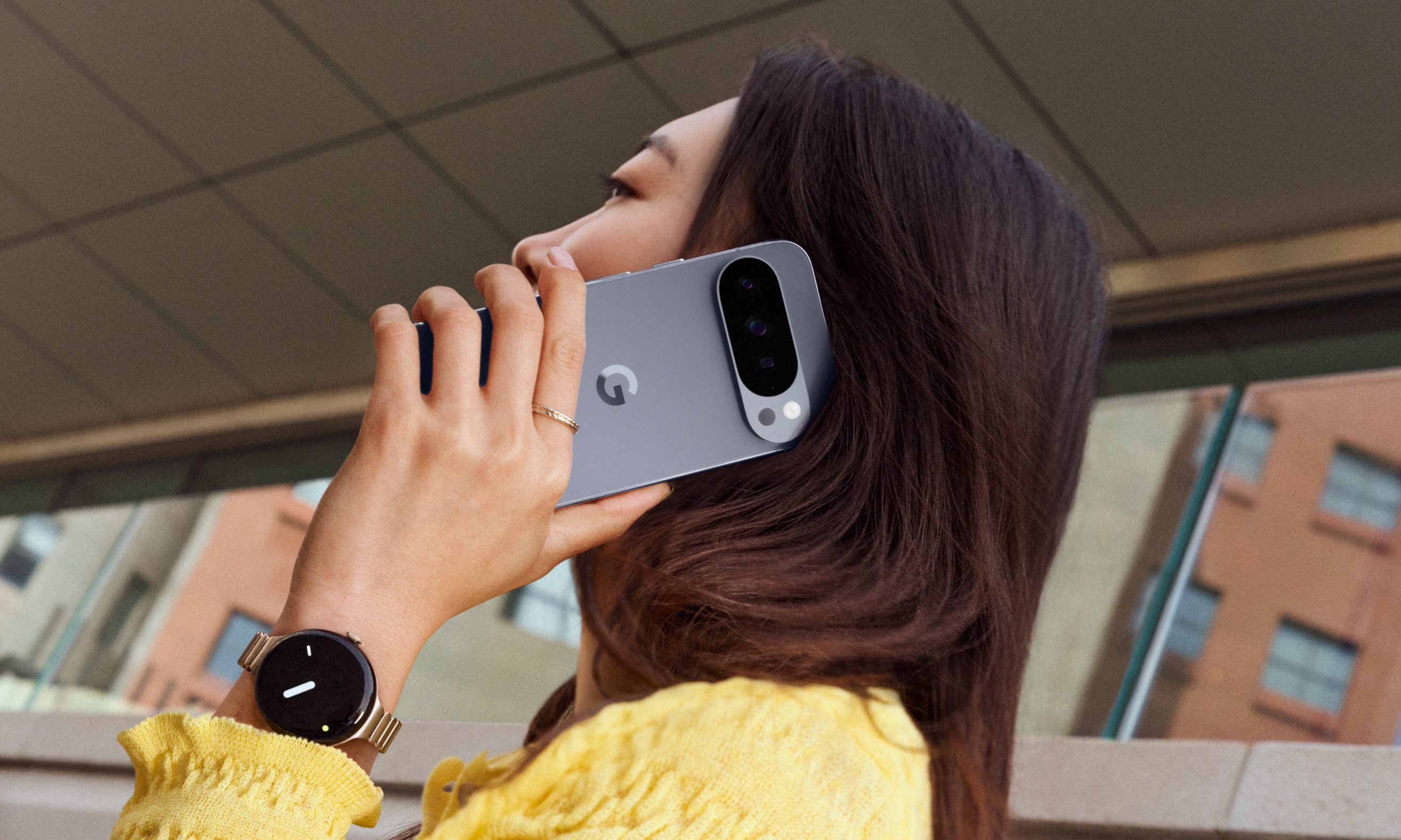 A person in a yellow top holding the Pixel 10 Pro to their ear