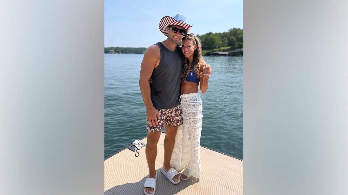 Jana Kramer poses on a dock with husband Allan Russell while wearing a blue bikini top and white crochet cover-up skirt during Fourth of July weekend.