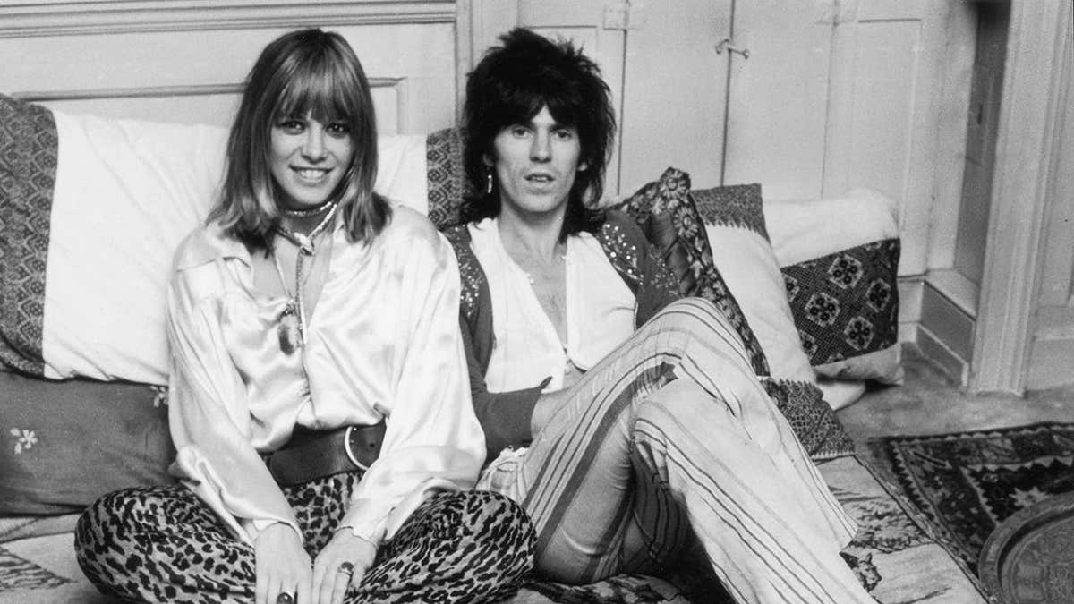 Anita Pallenberg and Keith Richards sitting in bed smiling.