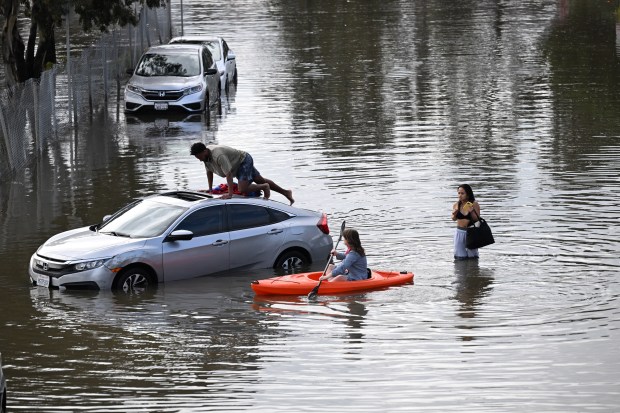 Emily Drake of Corte Madera paddles to help people stranded in a flooded area of Nellen Avenue near Lucky Drive in Corte Madera, Calif., on Friday, Jan. 2, 2026. (Sherry LaVars/Marin Independent Journal)