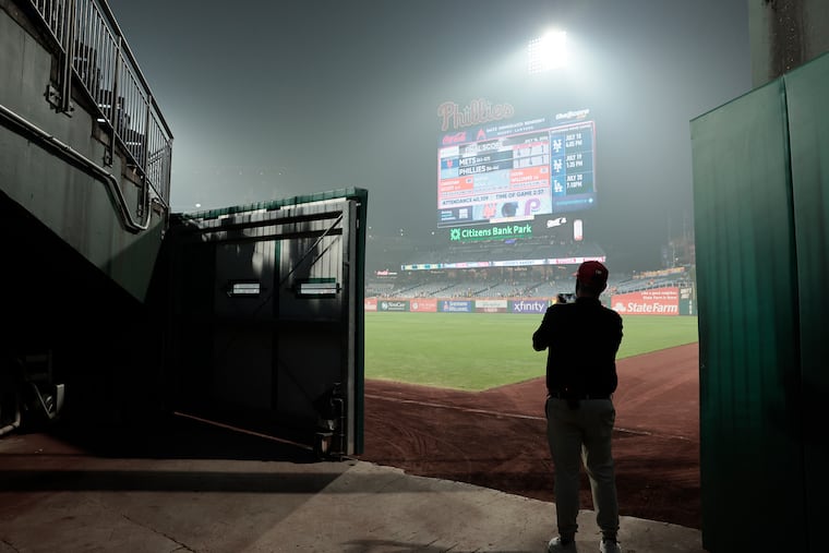 Phils logistics team member Erik Lowell takes a photo of the smoke filled air over the baseball field after the New York Mets at Philadelphia Phillies MLB baseball game at Citizens Bank Park in Philadelphia.