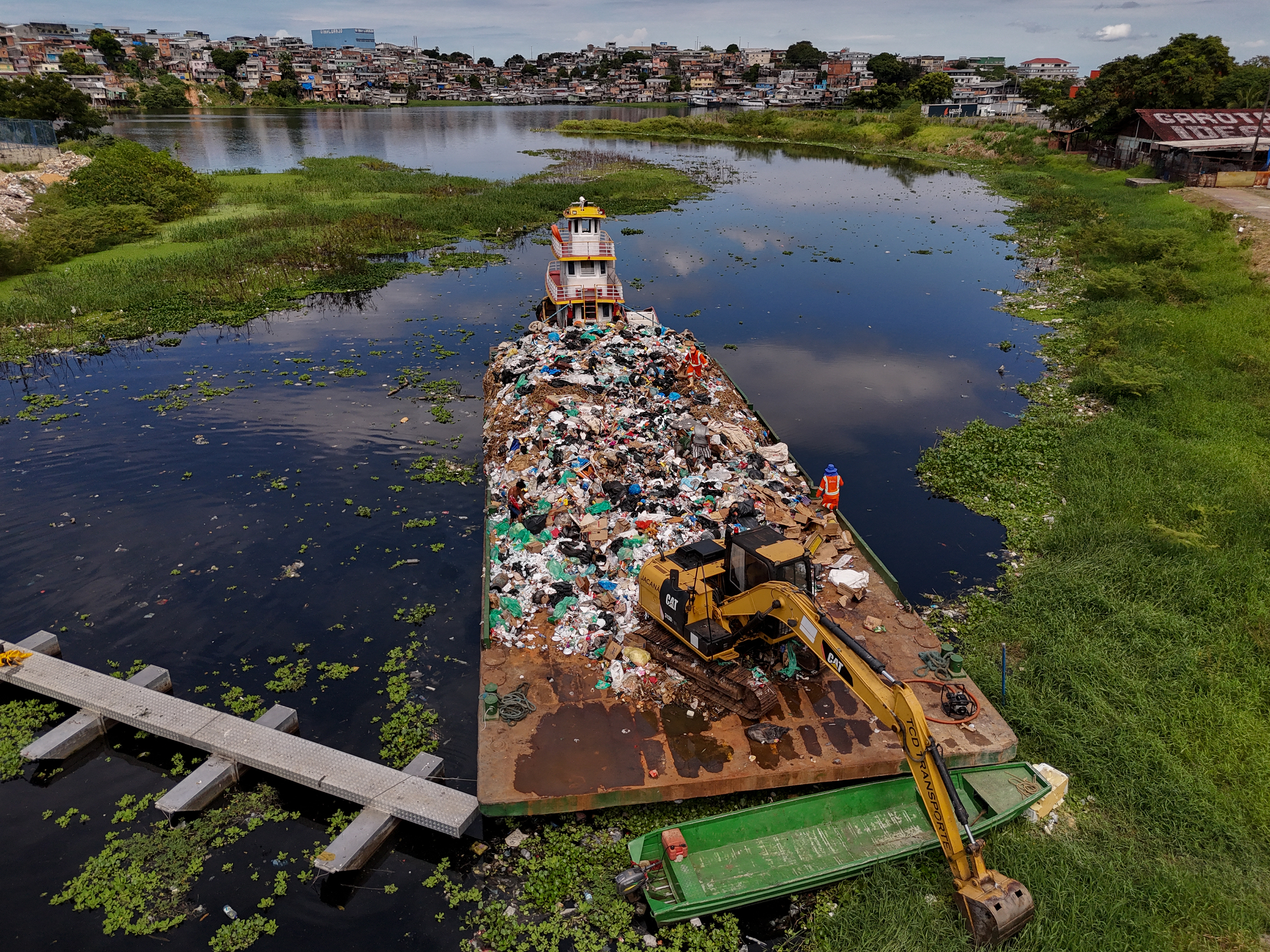 TOPSHOT - An aerial view shows a barge carrying a large amount of trash removed from the Rio Negro in Manaus, Amazonas state, northern Brazil, on July 7, 2026. Recent studies indicate alarming concentrations of microplastics along the banks of the Rio Negro, near the Manaus waterfront. (Photo by MICHAEL DANTAS / AFP via Getty Images)