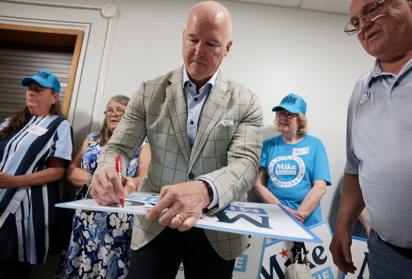 Mike Minogue autographs a campaign sign for Frederick Holt, right, after turning in signatures in May to qualify for the primary ballot.