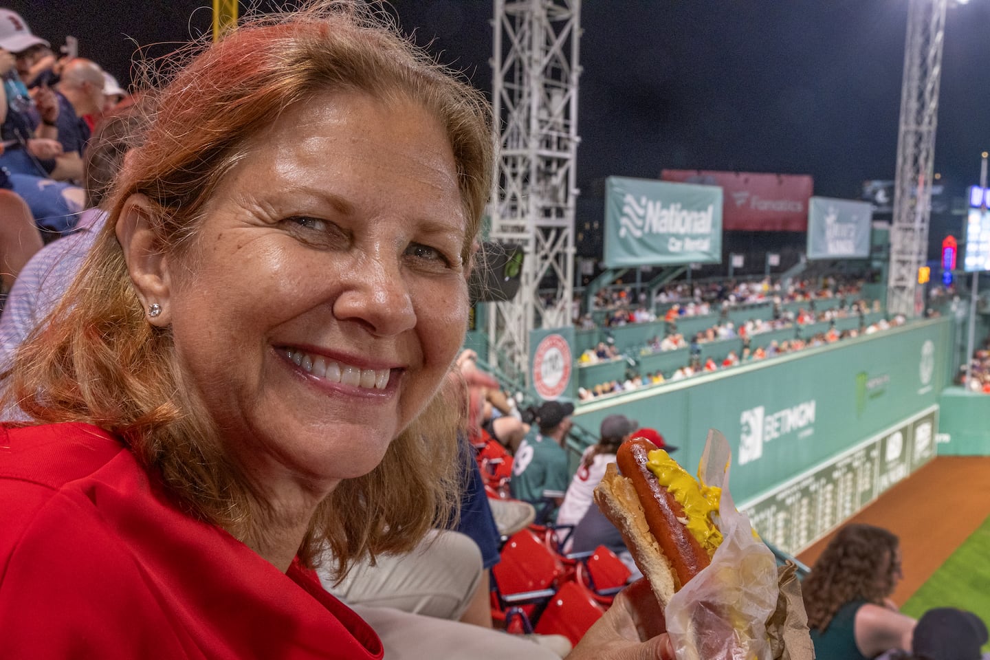 Smith is at home in Fenway Park, with a hot dog and a beer on the Pavilion level. Behind her are the seats she placed on top of the famed Green Monster.