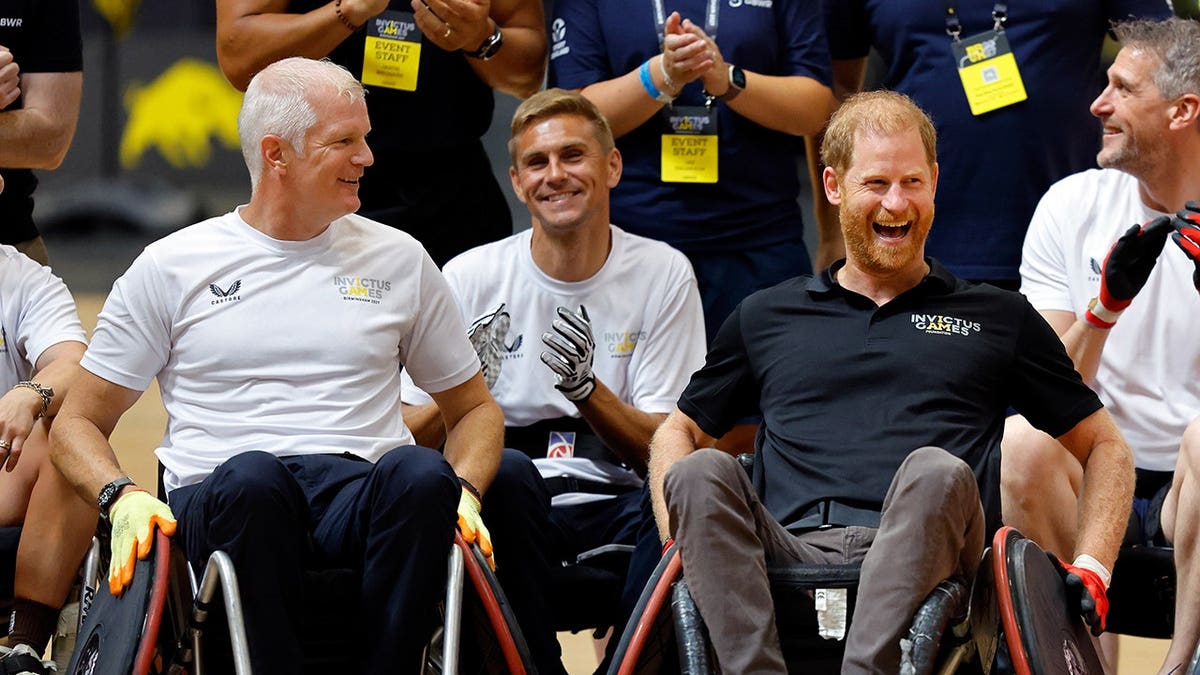Al Carns and Prince Harry play wheelchair rugby in a gymnasium.