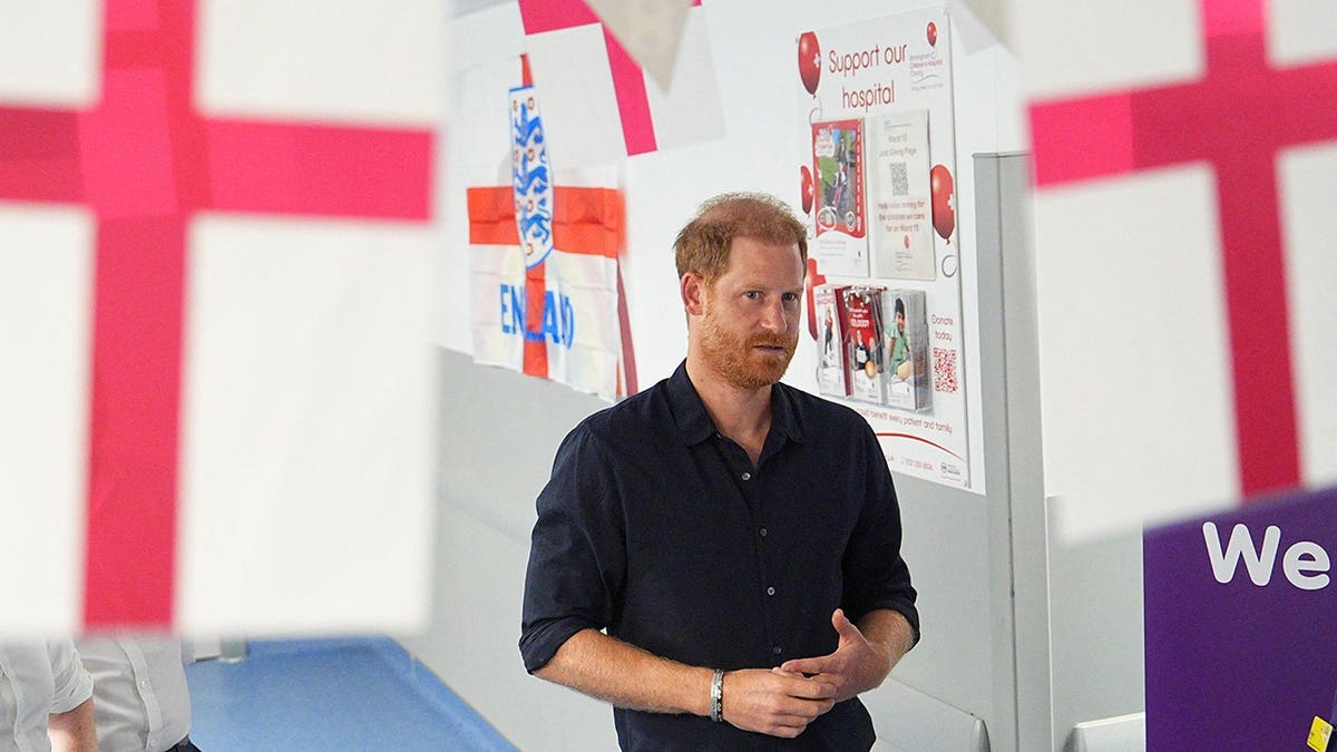 Prince Harry wearing a dark shirt inside a hospital in the UK.