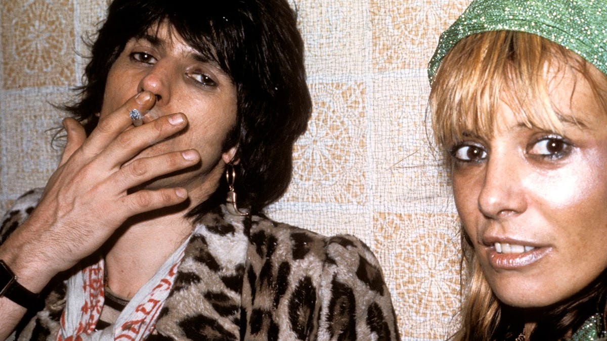 Keith Richards smoking while Anita Pallenberg looks on.