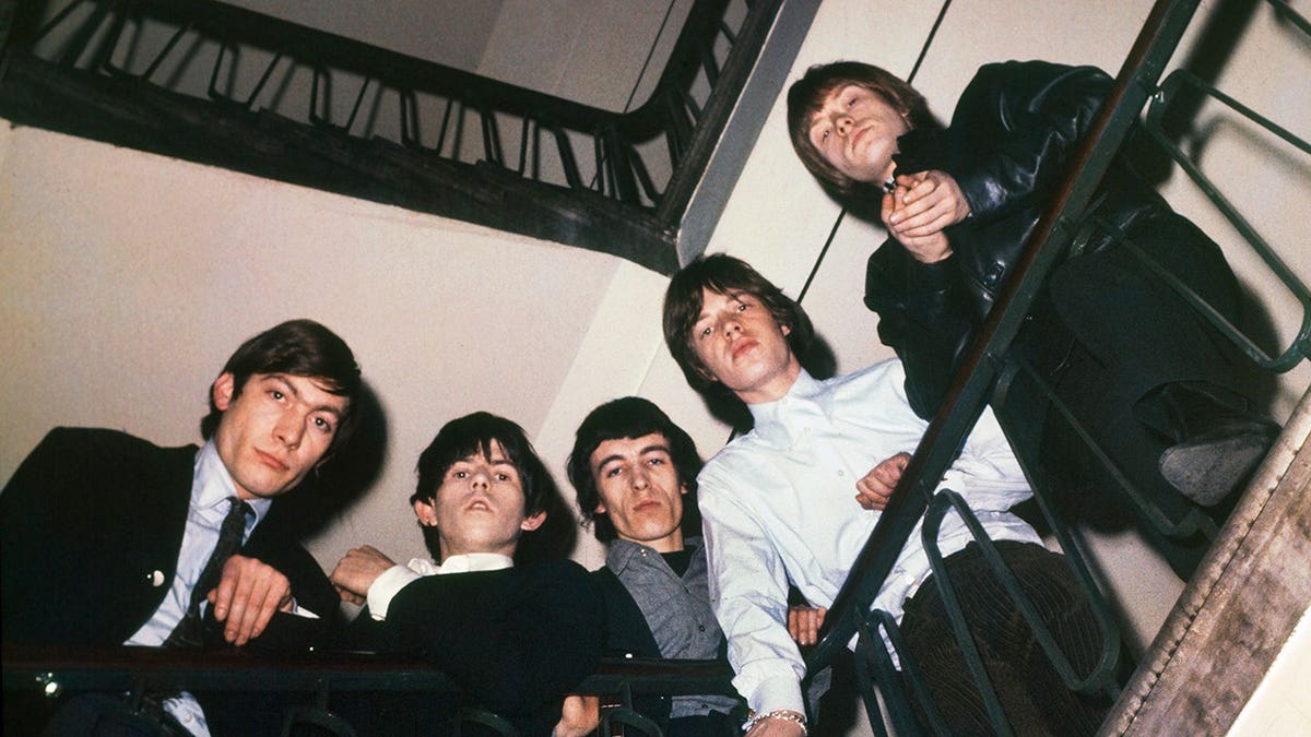 The Rolling Stones in 1965 looking down from a staircase.