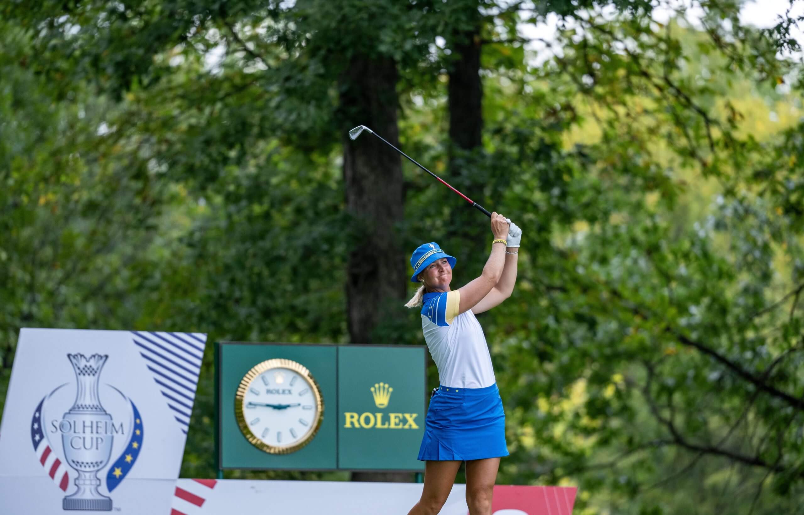 Anna Nordqvist, wearing a blue bucket hat and blue skirt, tees off 