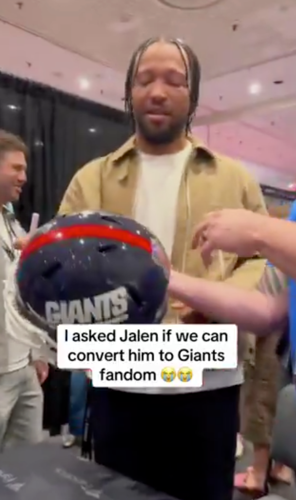 Jalen Brunson holding a football helmet with "GIANTS" written on the side.
