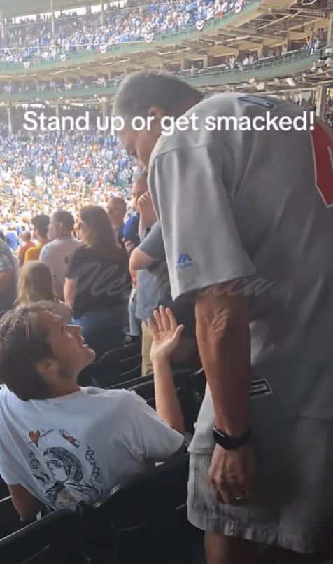 A fan at a Cubs fan made go slapping a young man for not standing during the national anthem. 