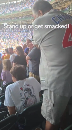 A fan at a Cubs fan made go slapping a young man for not standing during the national anthem. 