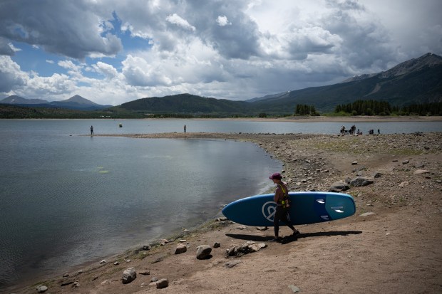 Silverthorne resident Jeni Engler carries her paddle board to the low banks of Dillon Reservoir on Thursday, July 9, 2026, in Dillon, Colo. (Photo by Timothy Hurst/The Denver Post)
