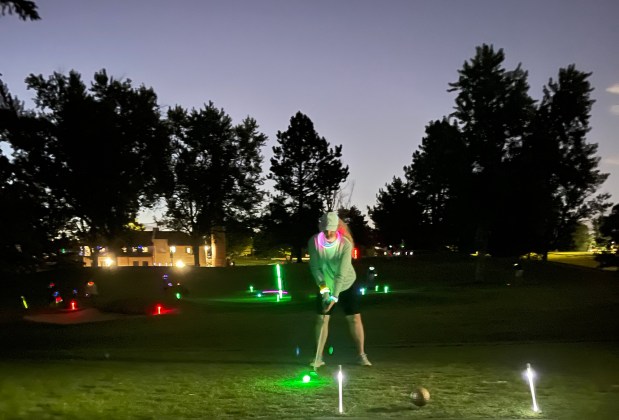 A golfer tees off during a glow ball round at night at Harvard Gulch in Denver. (TJ Hutchinson, The Denver Post)