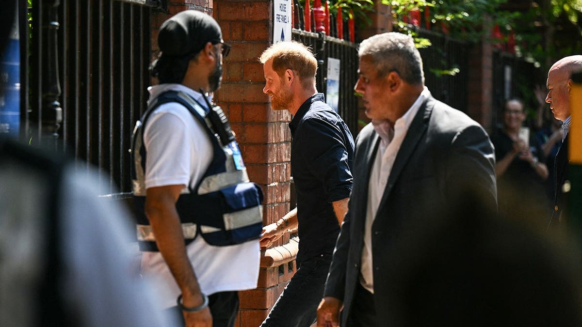 Prince Harry being accompanied by a body guard outdoors in the UK.