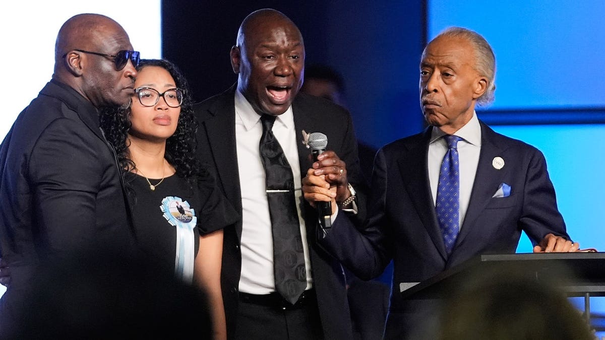 Attorney Ben Crump, center, speaks next to Elmore and Christine Wonsley, at left, and Rev. Al Sharpton