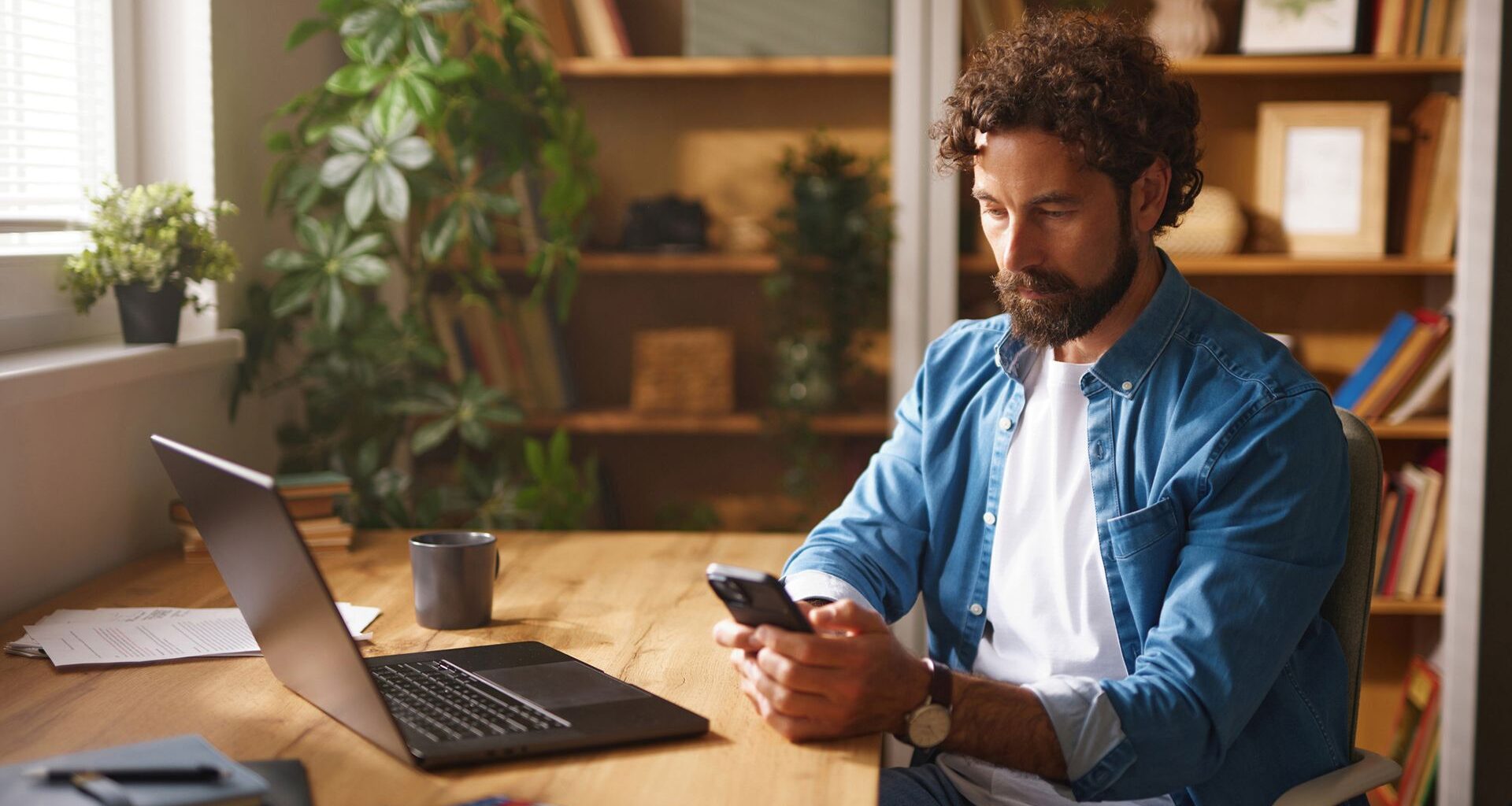 A man uses the phone as he sits by the desk