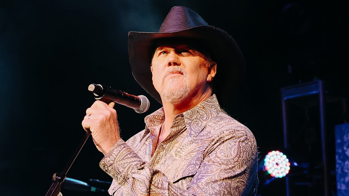 Trace Adkins performs in a paisley shirt and a black cowboy hat.