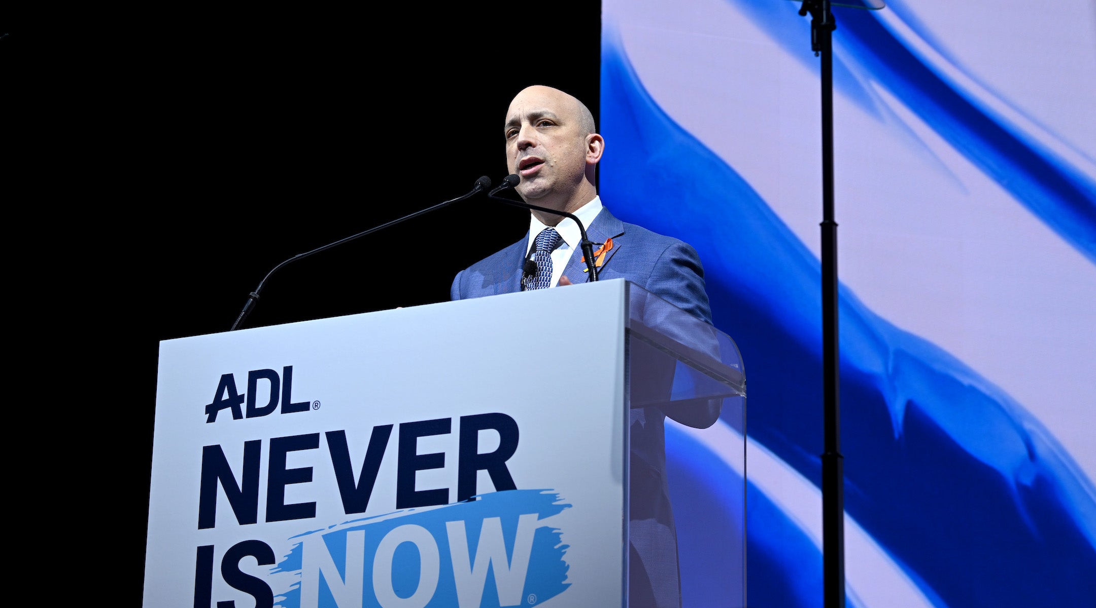 A photo of greenblatt speaking from a podium.