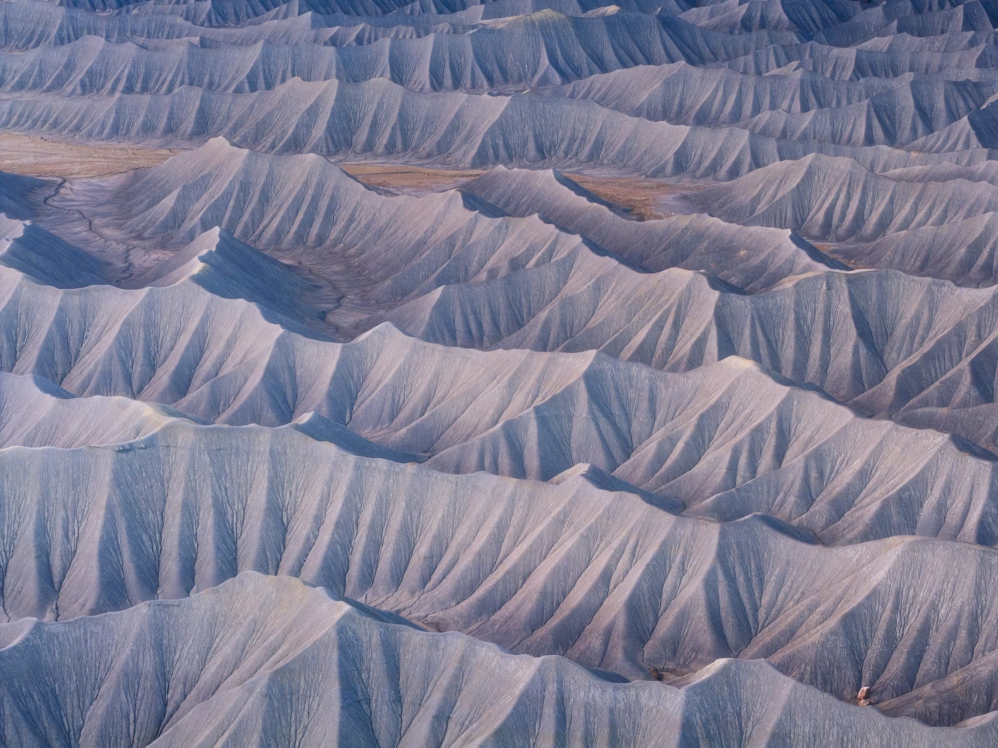 an aerial photograph of serrated ridges of a dry, desert landscape