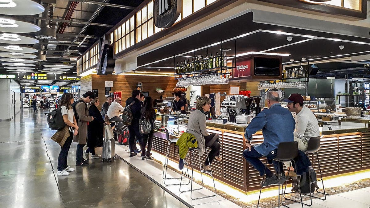 A group of people drinks at an airport bar.