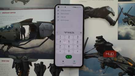 An Android phone set on an open artbook showing the dialer dialing a shortcode
