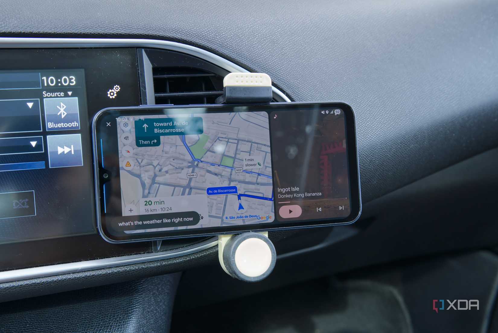 An Android phone showing the ANdroid Auto UI with Google Maps and Nintendo Music open side by side, as well as voice prompt showing the text "what's the weather like rioght now?"