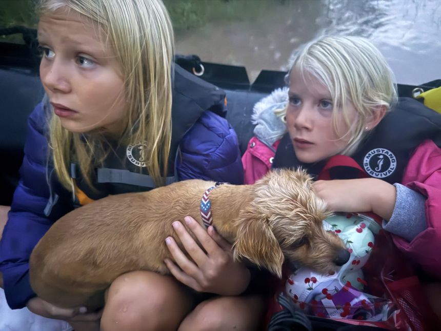 Ella and Grace Sanford and their dog Benjamin ride on a Texas Game Wardens rescue boat after being evacuated from their home in Uvalde, Texas, on Thursday.