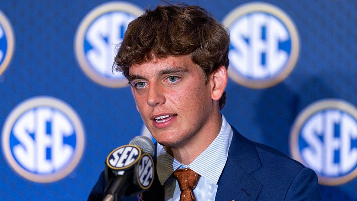Arch Manning, quarterback for the Texas Longhorns, speaks at a podium.