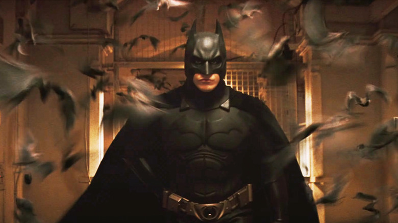 Bruce Wayne in his costume surrounded by bats in Batman Begins