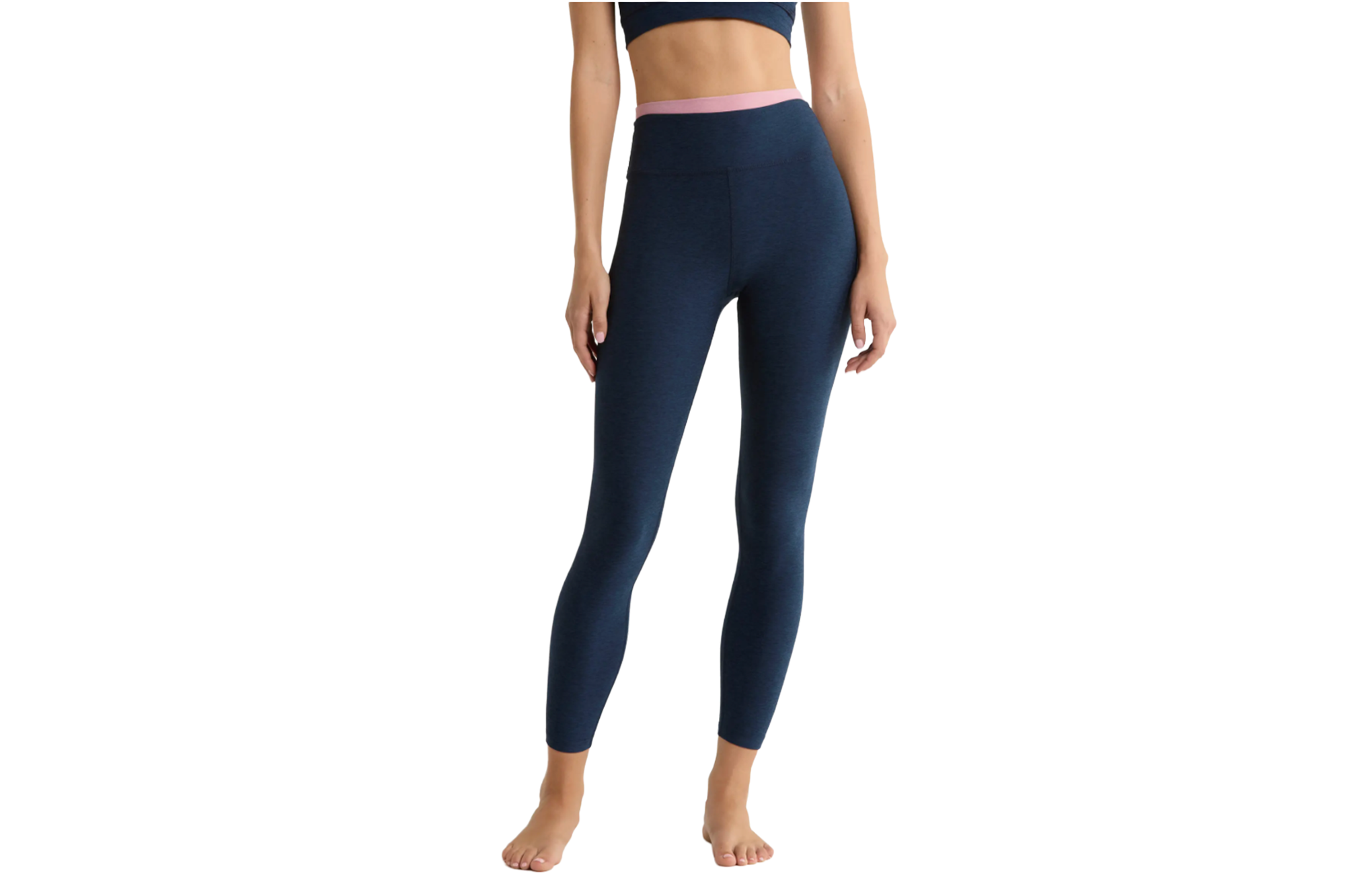 Model wearing dark blue yoga pants with a light pink waistline and a matching dark blue bra.
